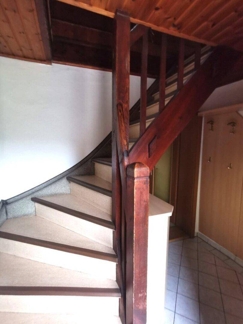 Holztreppe mit gefliestem Boden im Flur, der zu weiteren Räumen führt.