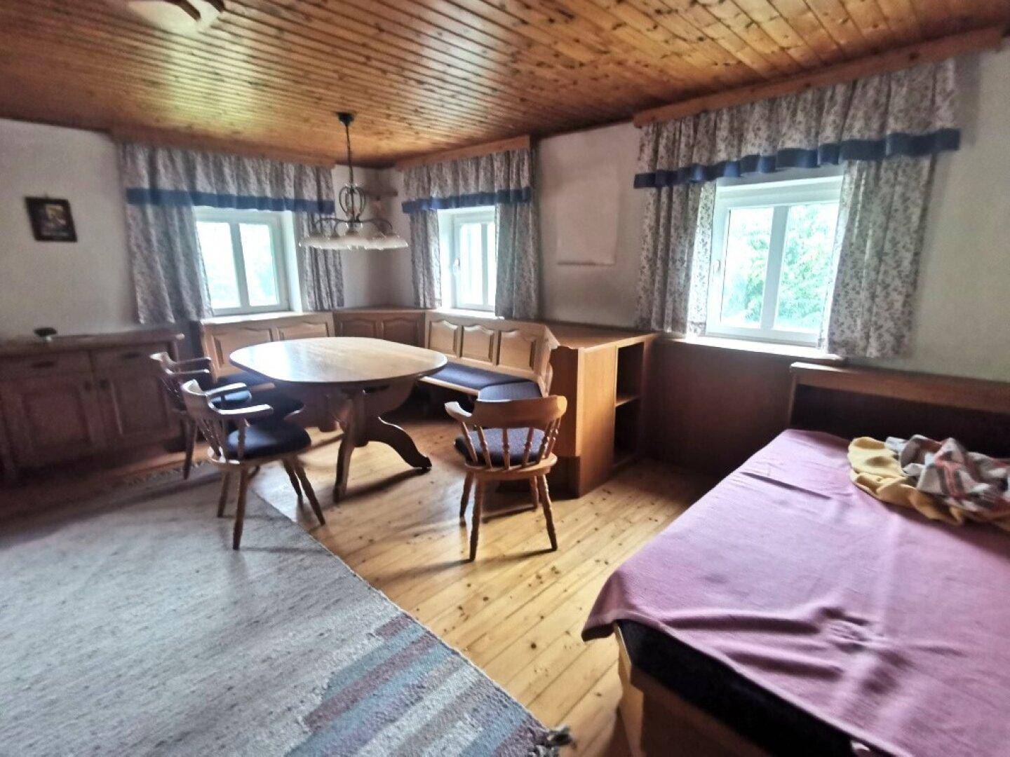 Rustikaler Wohn- und Essbereich mit Holzboden, Holzdecke und traditionellen Möbeln, inklusive Schlafgelegenheit.