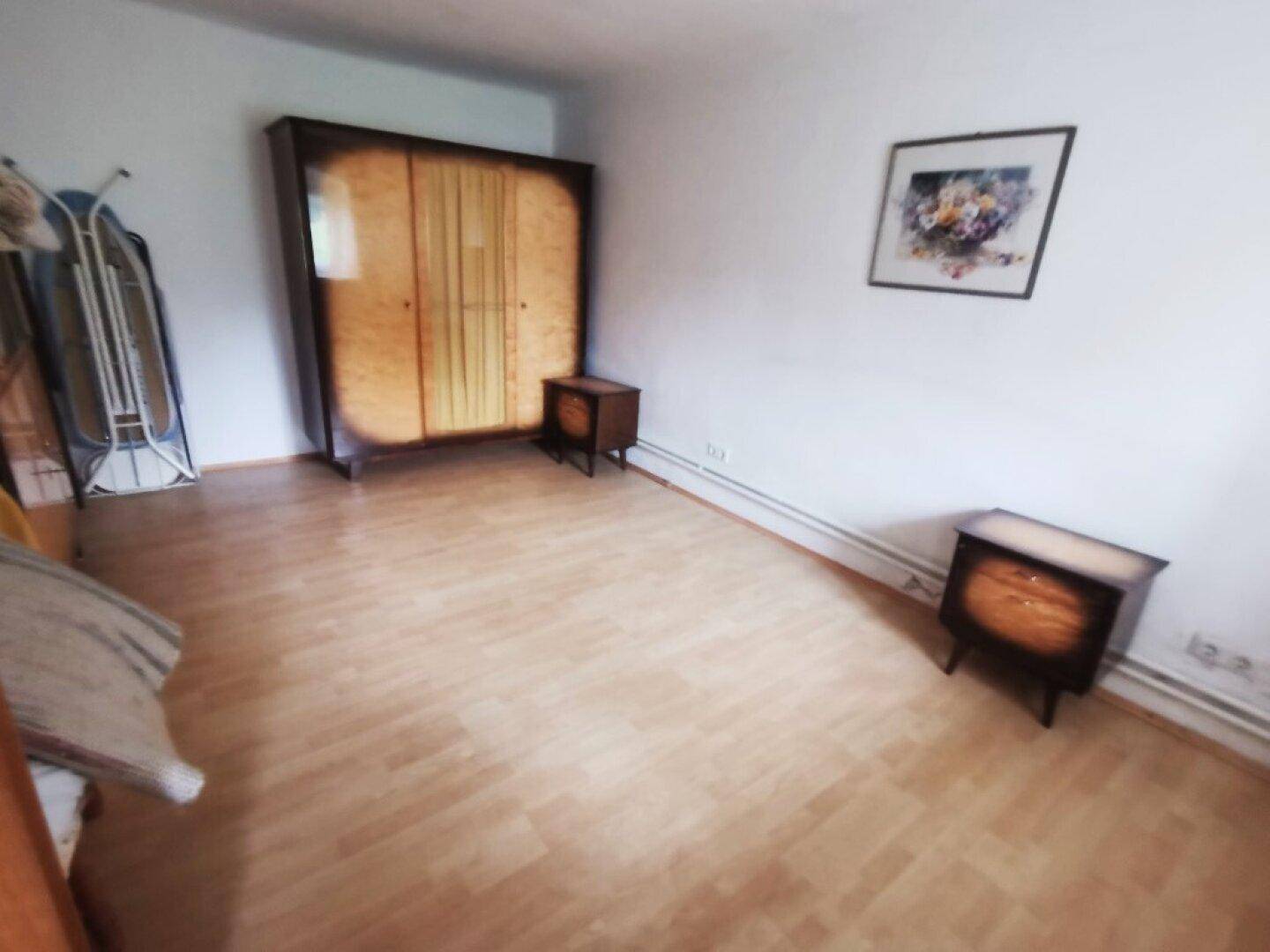 Einfaches Schlafzimmer mit Laminatboden, einem Kleiderschrank und zwei Nachttischen.