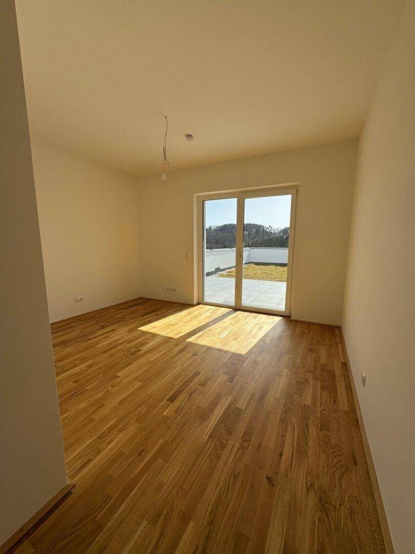 Sonniges Schlafzimmer mit Holzboden und direktem Zugang zu einer privaten Terrasse.