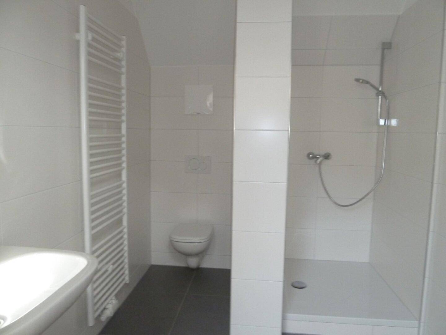 Modernes Badezimmer mit weißen Fliesen, Dusche und beheiztem Handtuchhalter.