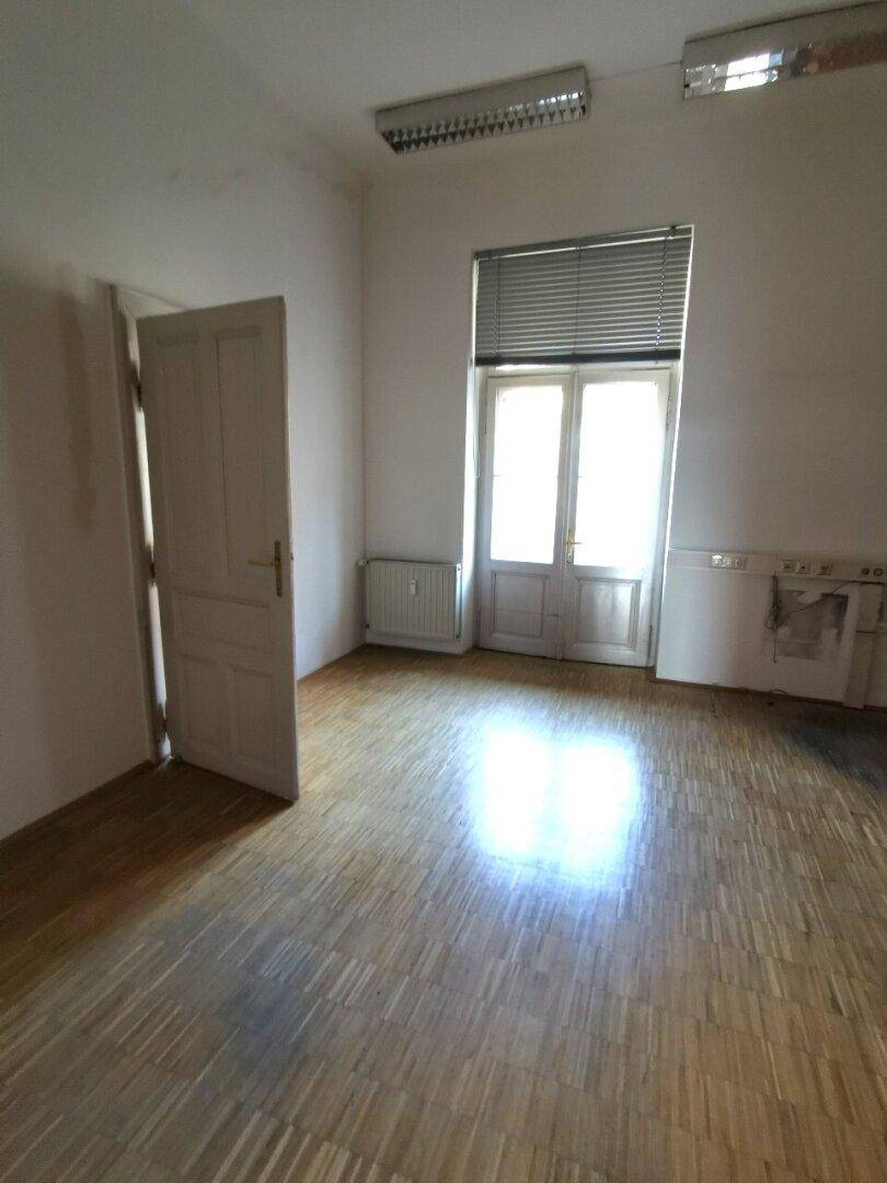 Heller Raum mit Holzboden, großer Doppeltür und Deckenleuchten, ideal für gewerbliche Nutzung.