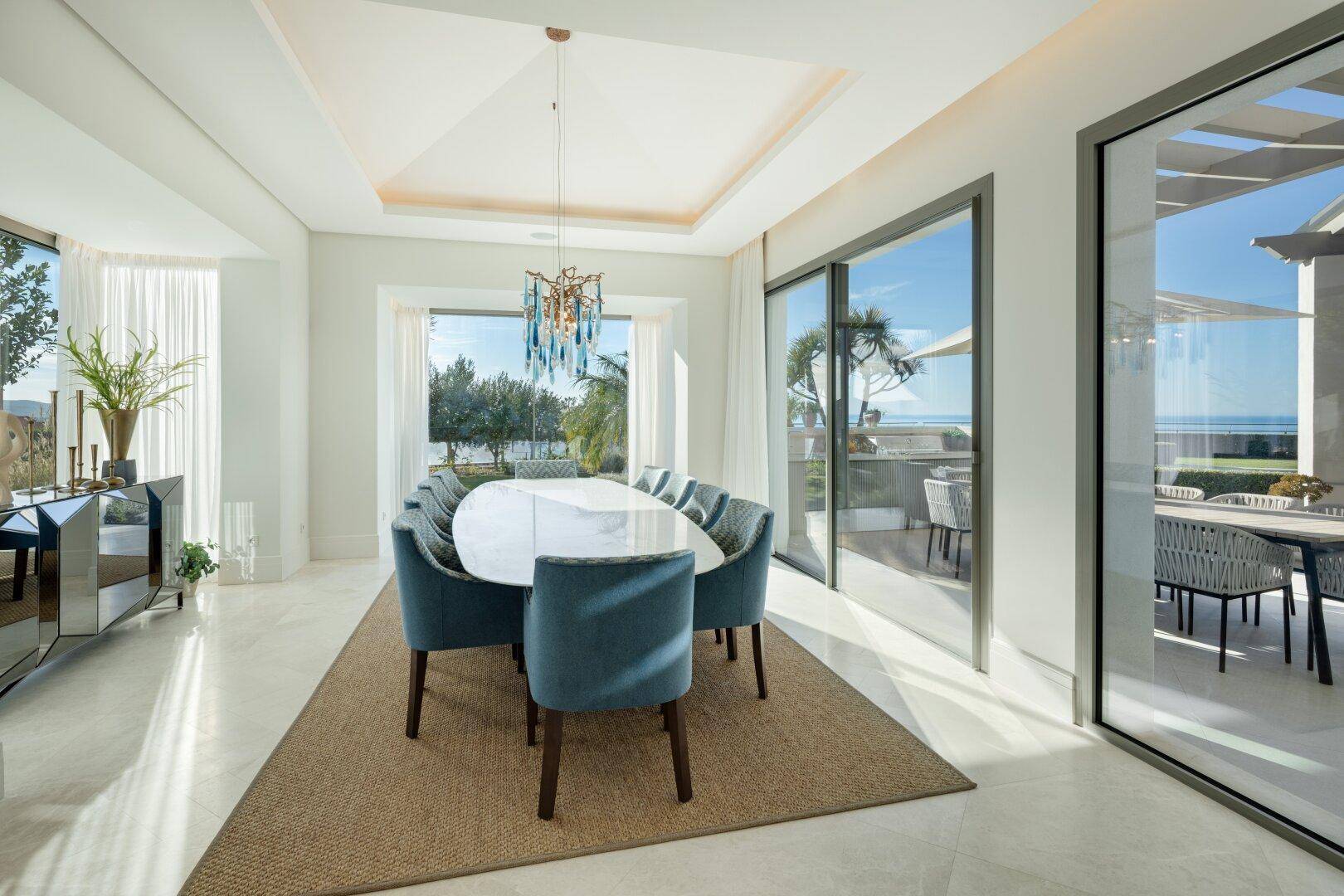 Eleganter Essbereich mit großem Tisch, Meerblick und Zugang zur Außenterrasse.
