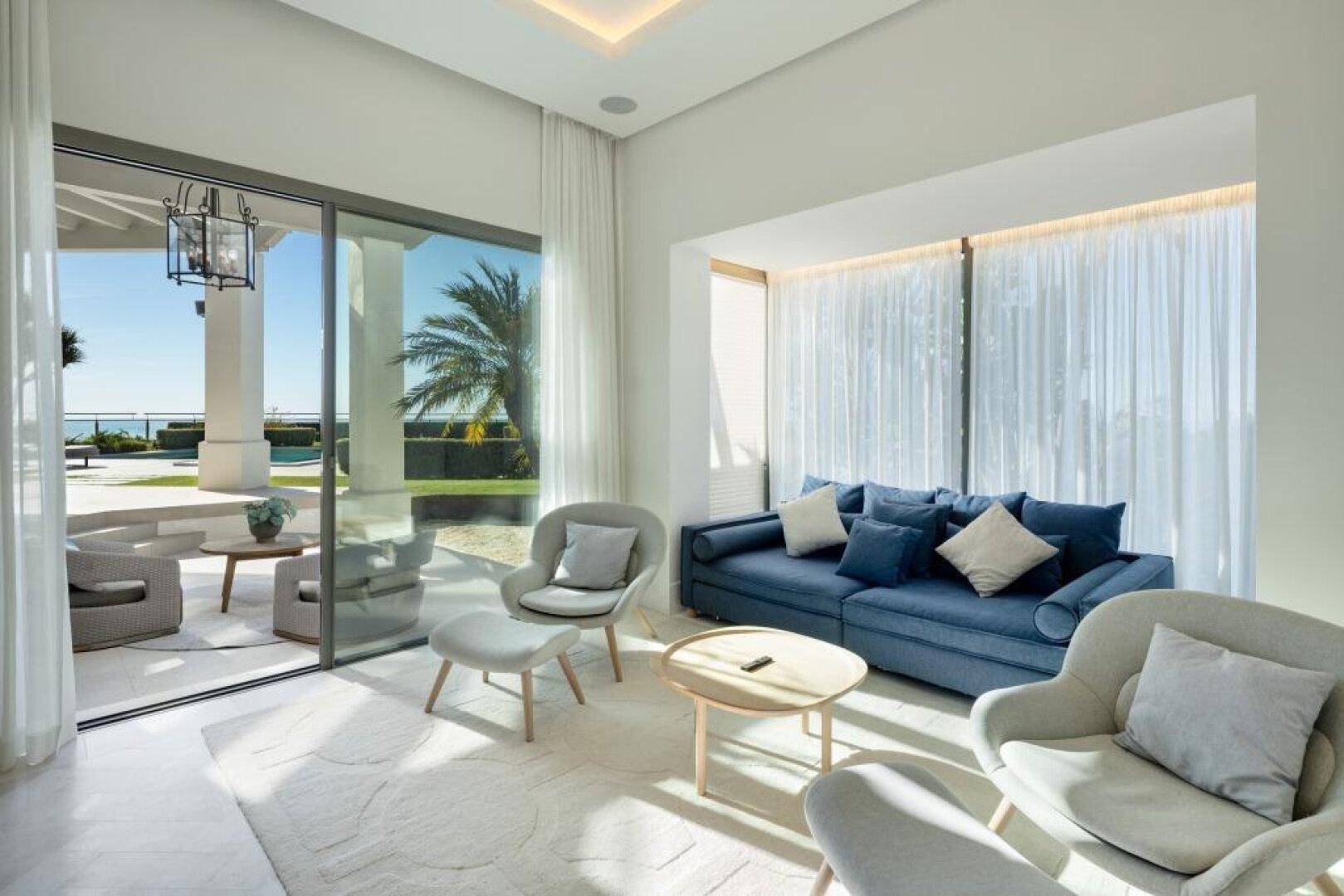 Gemütliches Wohnzimmer mit blauen Sofas, großen Fenstern und Meerblick.