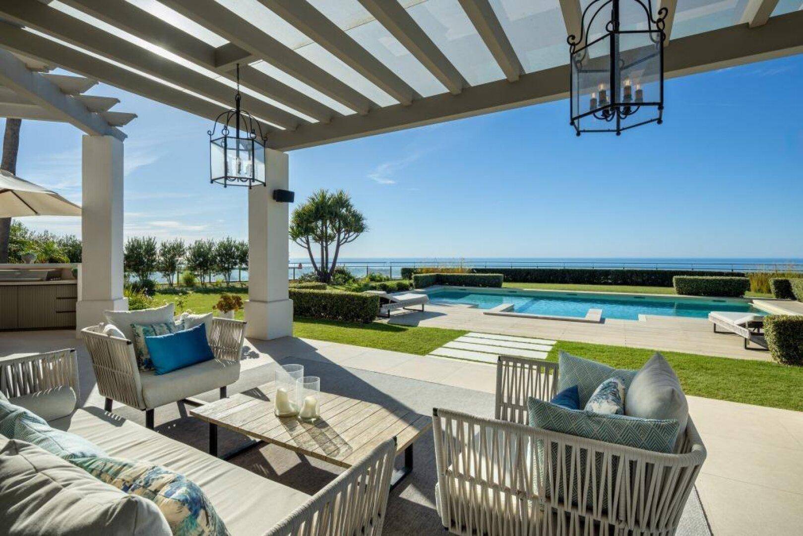 Überdachte Terrasse mit Lounge-Möbeln, Meerblick und Zugang zum Poolbereich.