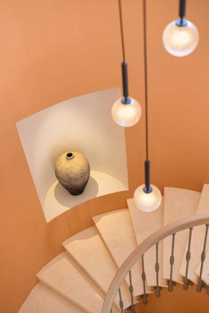 Detailaufnahme einer geschwungenen Treppe mit Dekoration und Pendelleuchten.