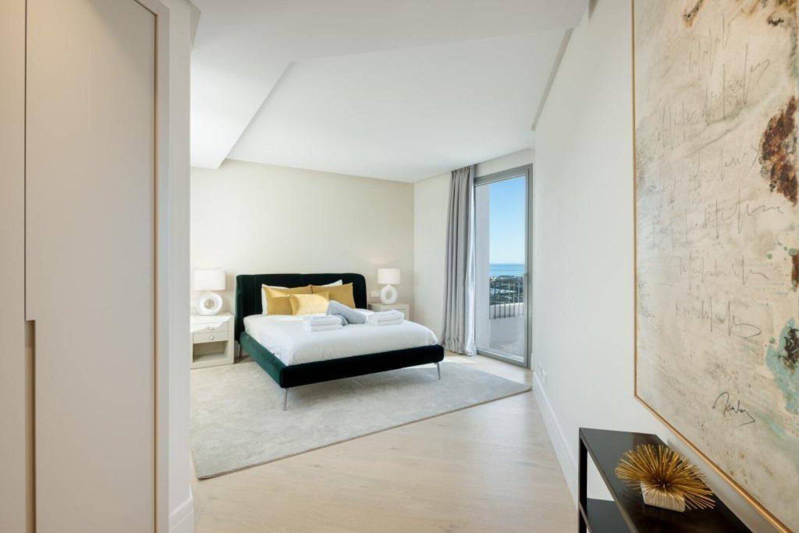 Modernes Schlafzimmer mit Balkonzugang und Blick auf das Meer.