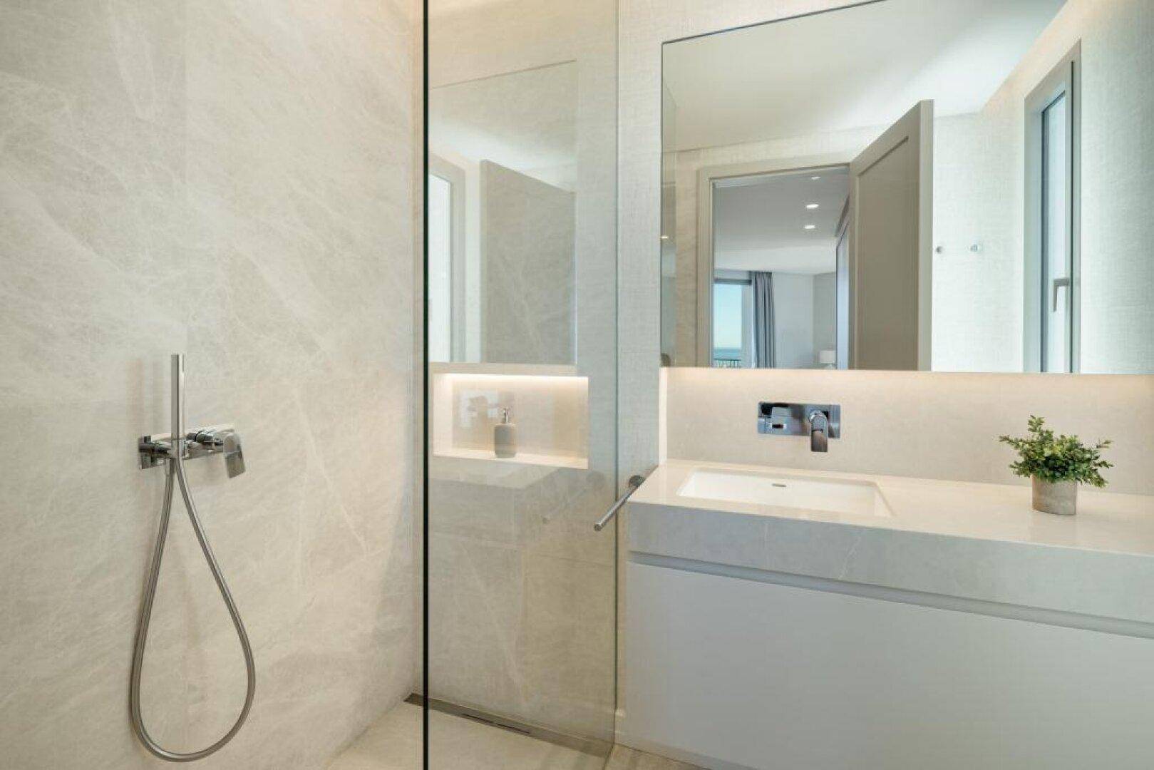 Modernes Badezimmer mit begehbarer Dusche, eleganten Fliesen und einem einzelnen Waschbecken.
