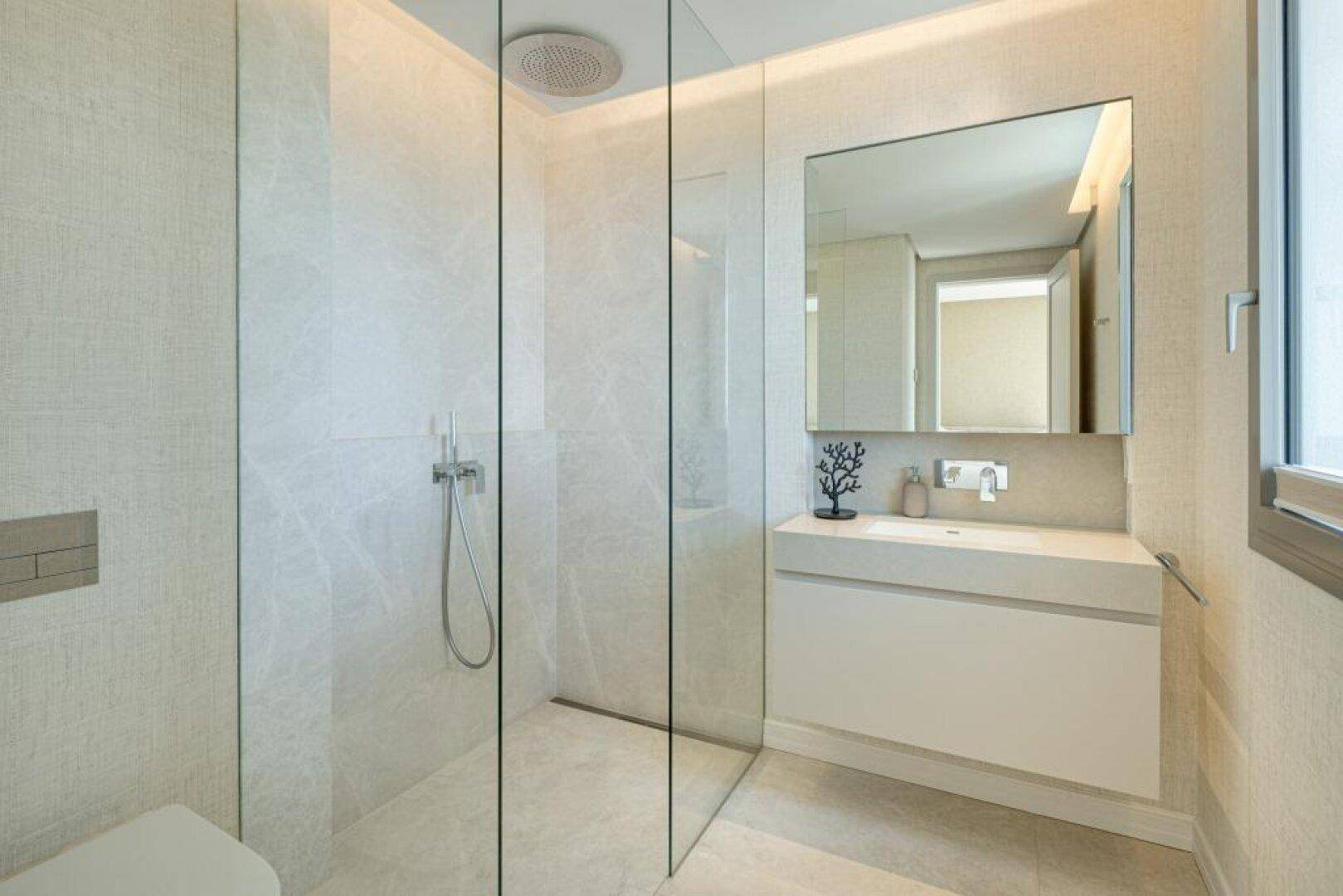 Elegantes Badezimmer mit begehbarer Dusche, modernem Waschbecken und hochwertigen Wandfliesen.