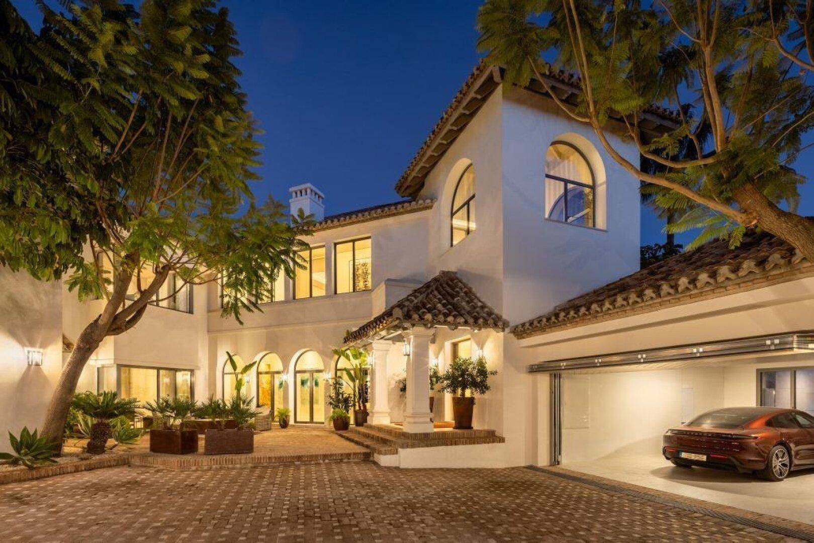 Beeindruckende Villa bei Dämmerung mit beleuchtetem Eingangsbereich und integrierter Garage.