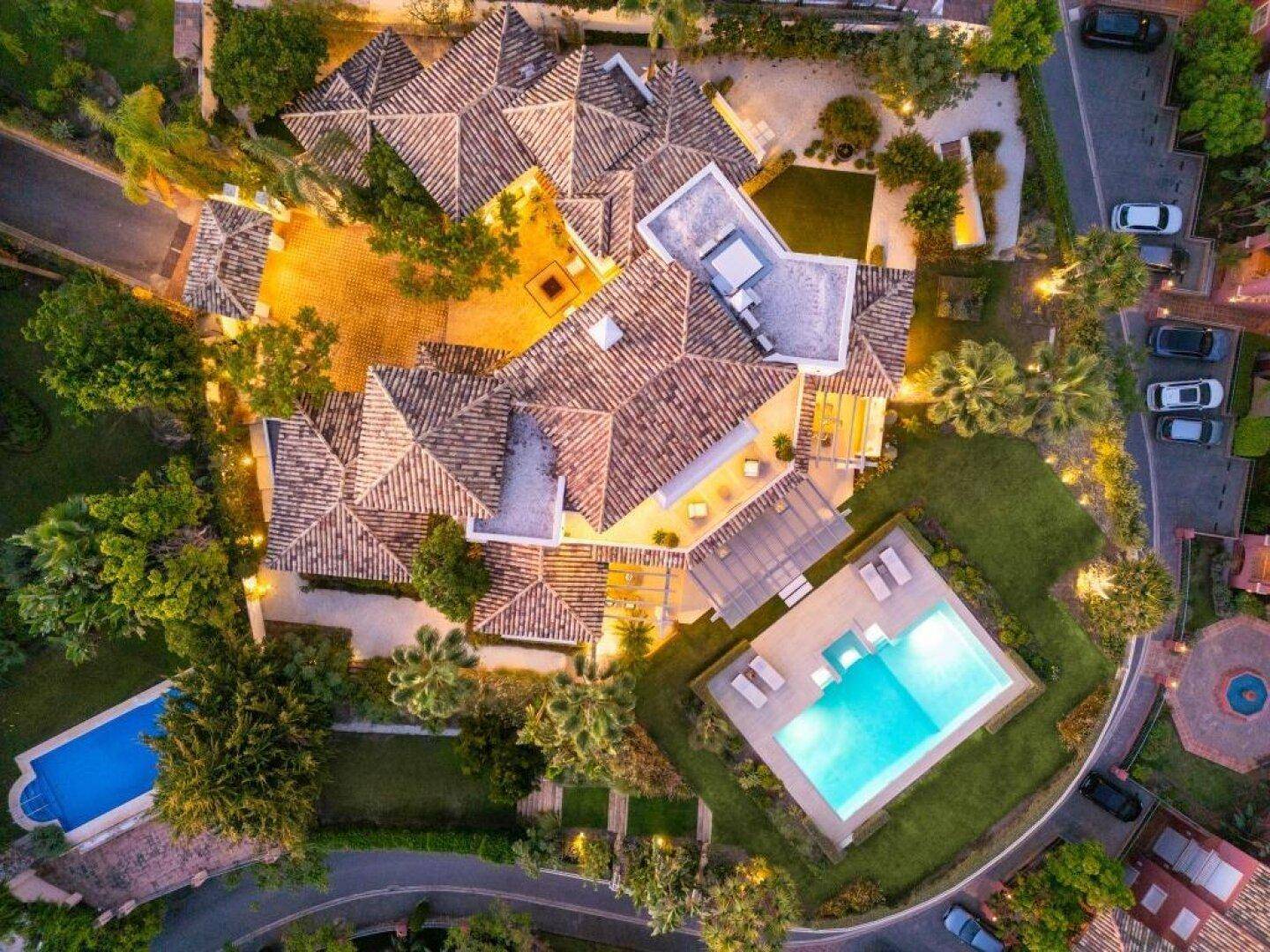 Vogelperspektive der Villa mit traditionellen Dächern, Poolbereich und gepflegtem Garten.