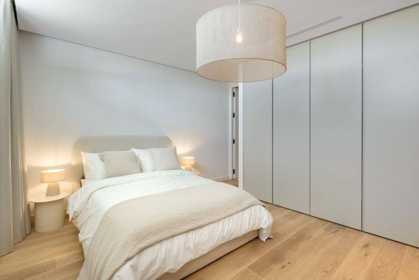 Ruhiges Schlafzimmer mit Holzboden, Einbauschränken und indirekter Beleuchtung.