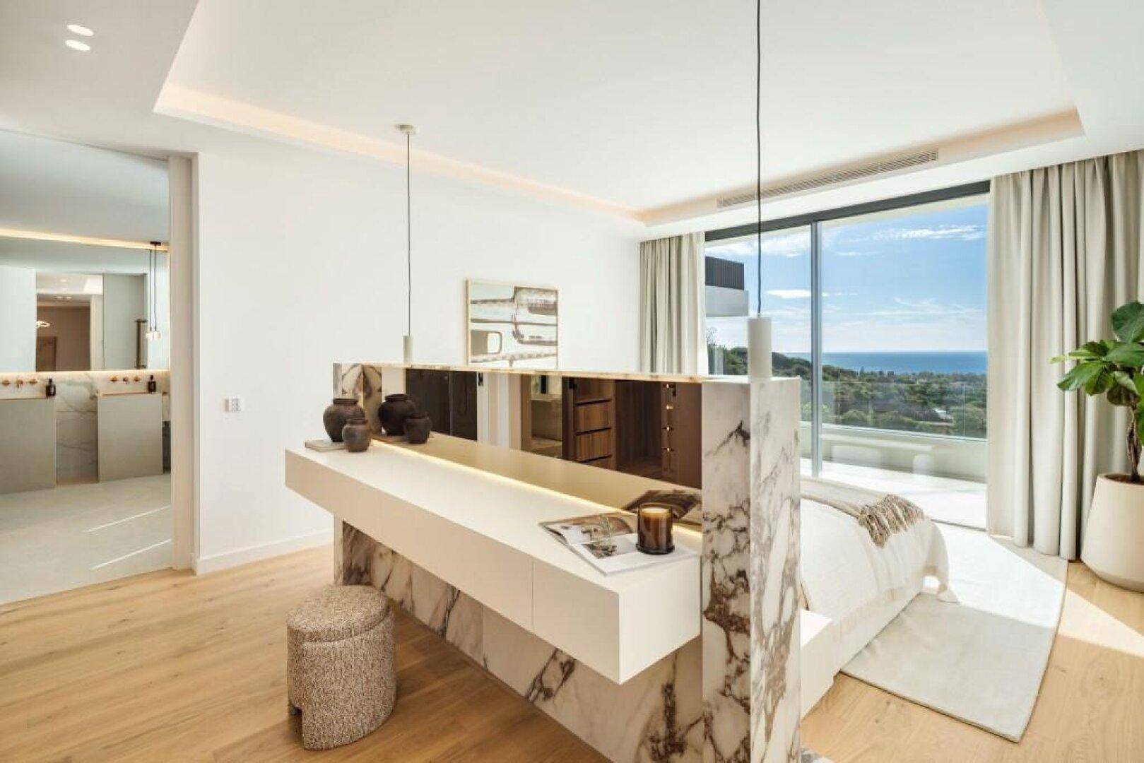 Modernes Schlafzimmer mit Meerblick, Marmorakzenten und direktem Zugang zum luxuriösen Badezimmer.