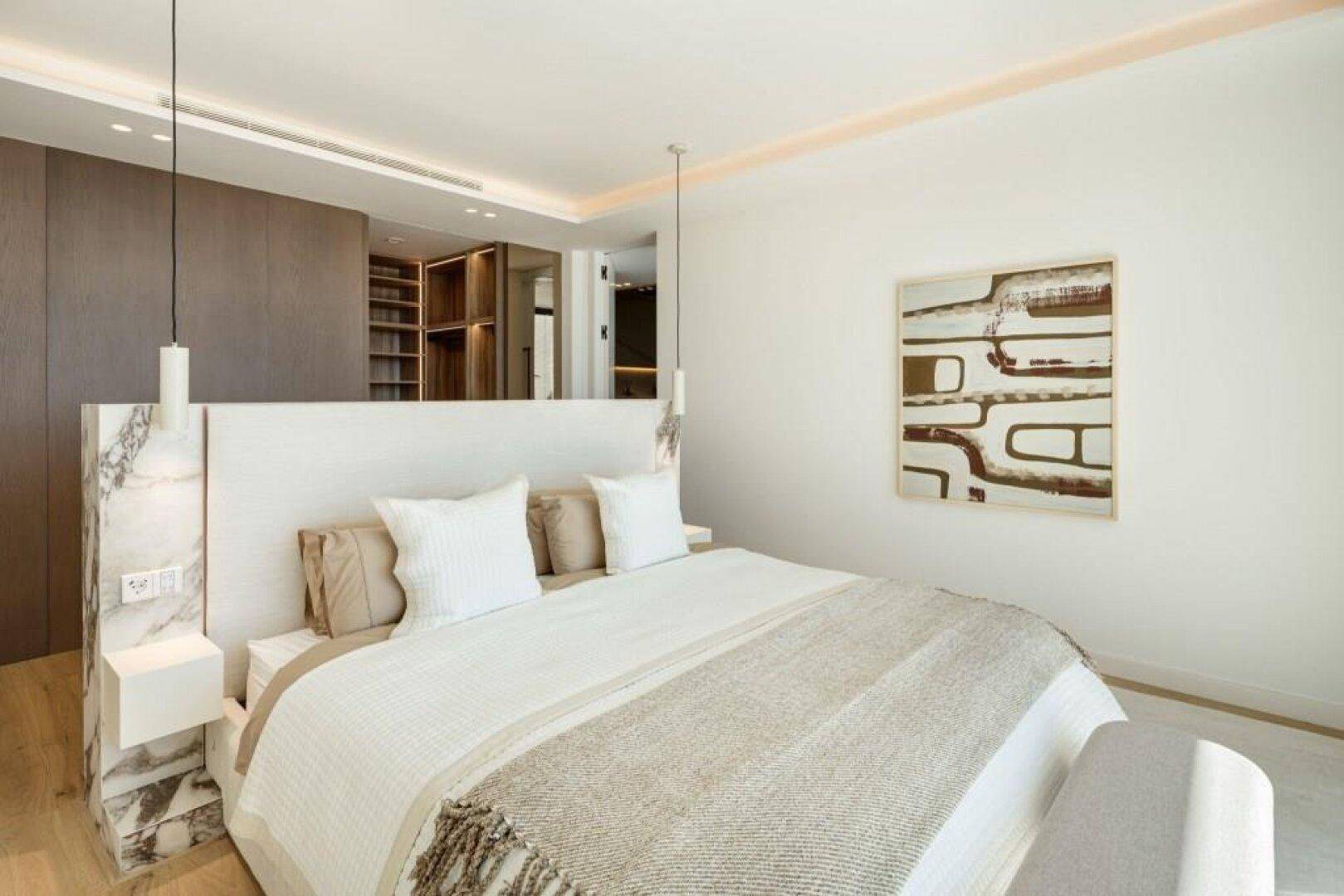 Elegantes Schlafzimmer mit großem Bett, Marmor-Kopfteil und integrierten Holzschränken für luxuriösen Komfort.