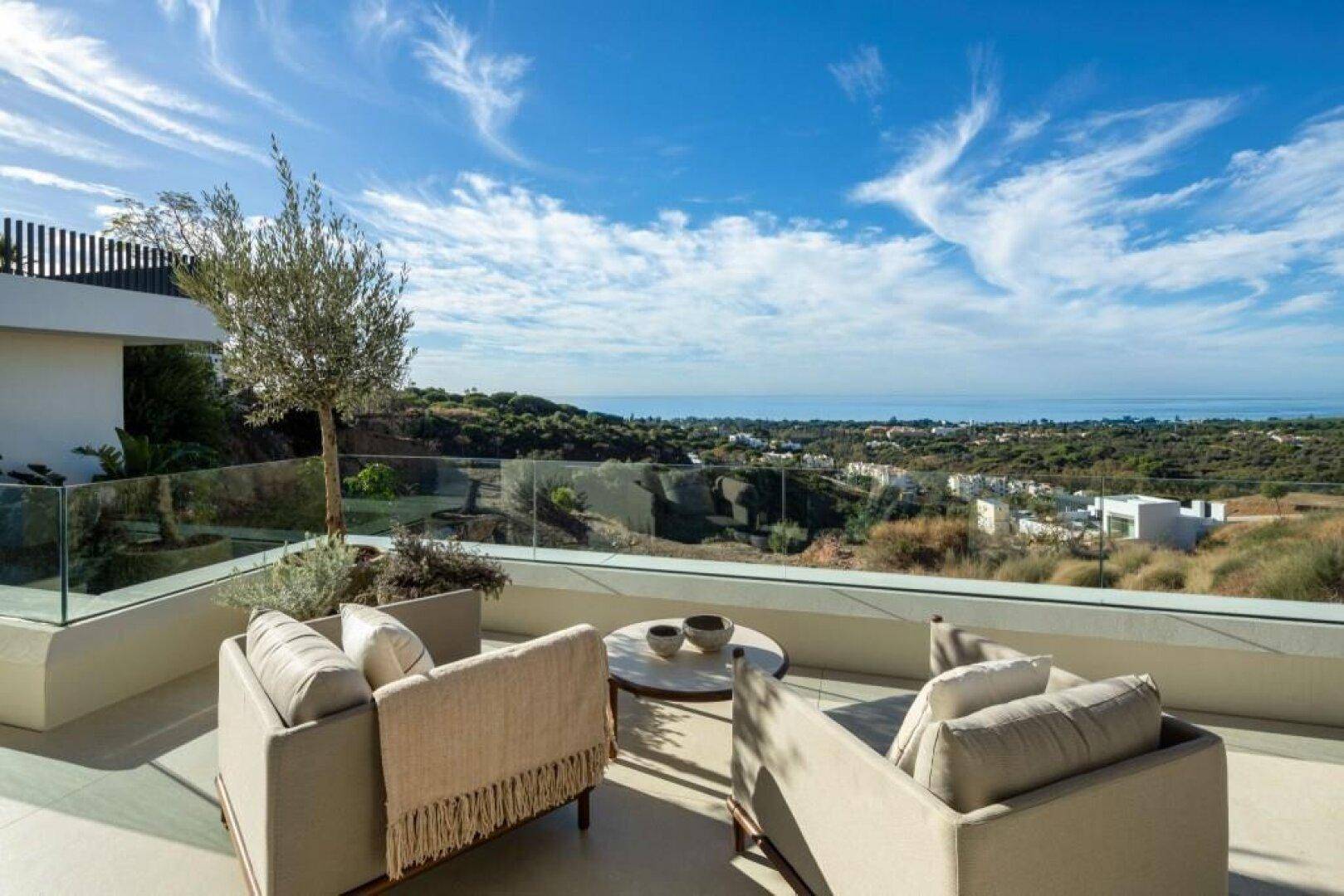 Geräumige Terrasse mit bequemen Sitzgelegenheiten und weitem Blick über die Landschaft bis zum Meer.