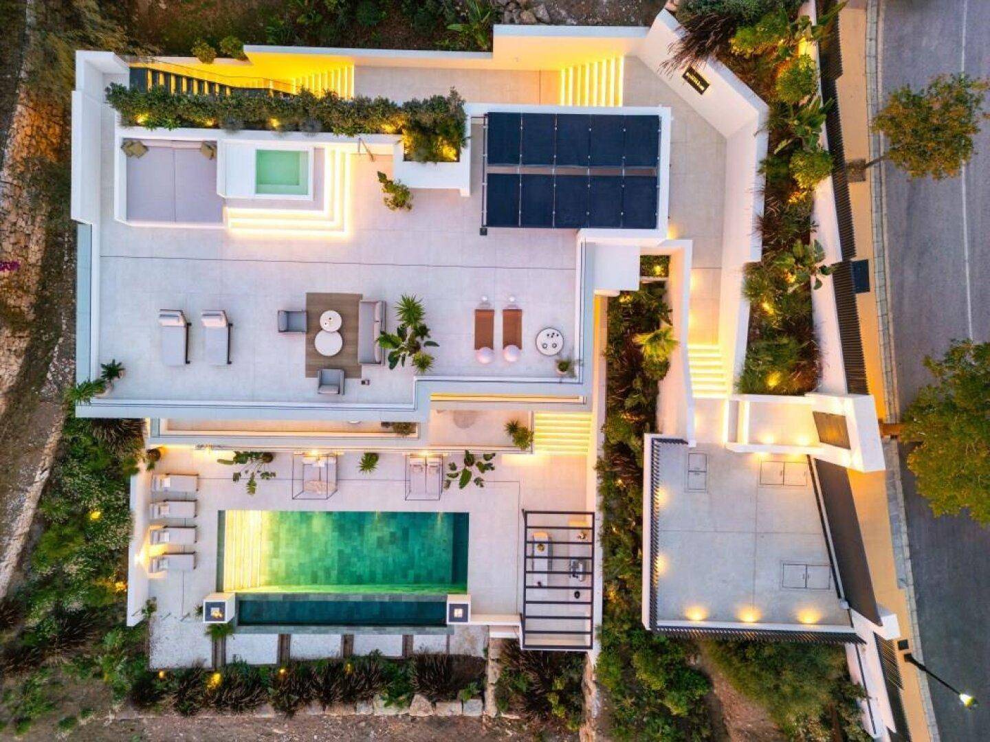 Vogelperspektive der modernen Villa mit weitläufigen Terrassen, Poolbereich und integrierten Solarmodulen.