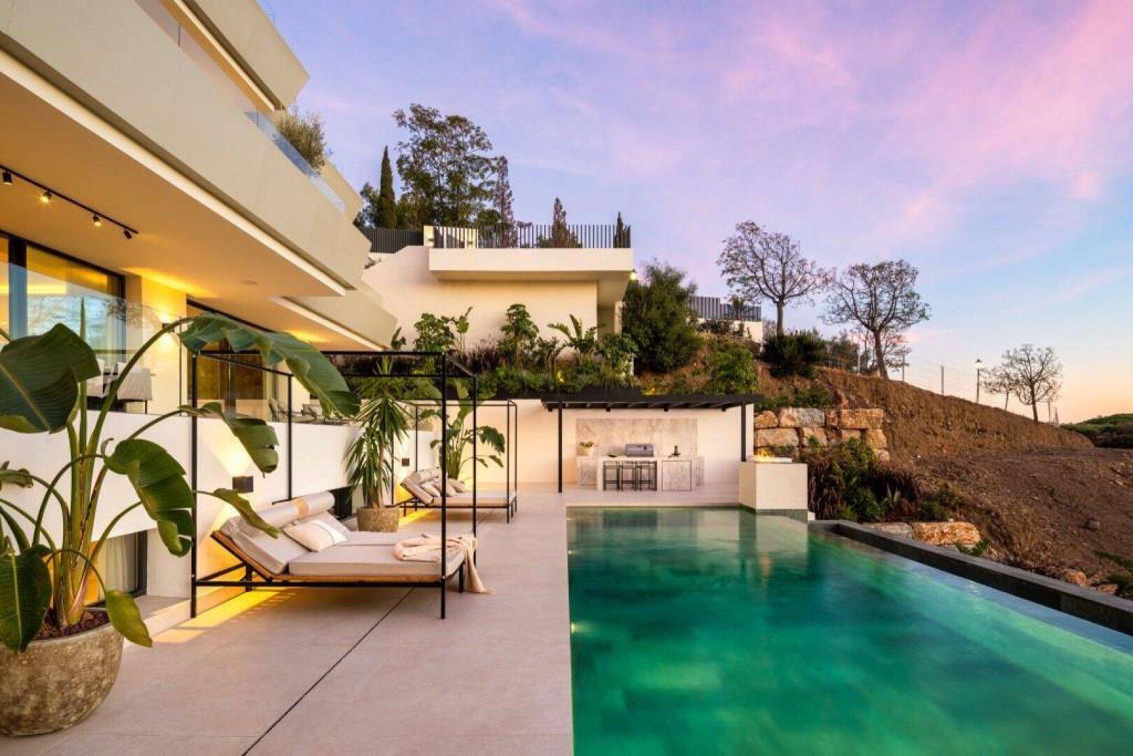 Die beleuchtete Villa bei Sonnenuntergang, mit glitzerndem Pool und stimmungsvoller Außenbeleuchtung.