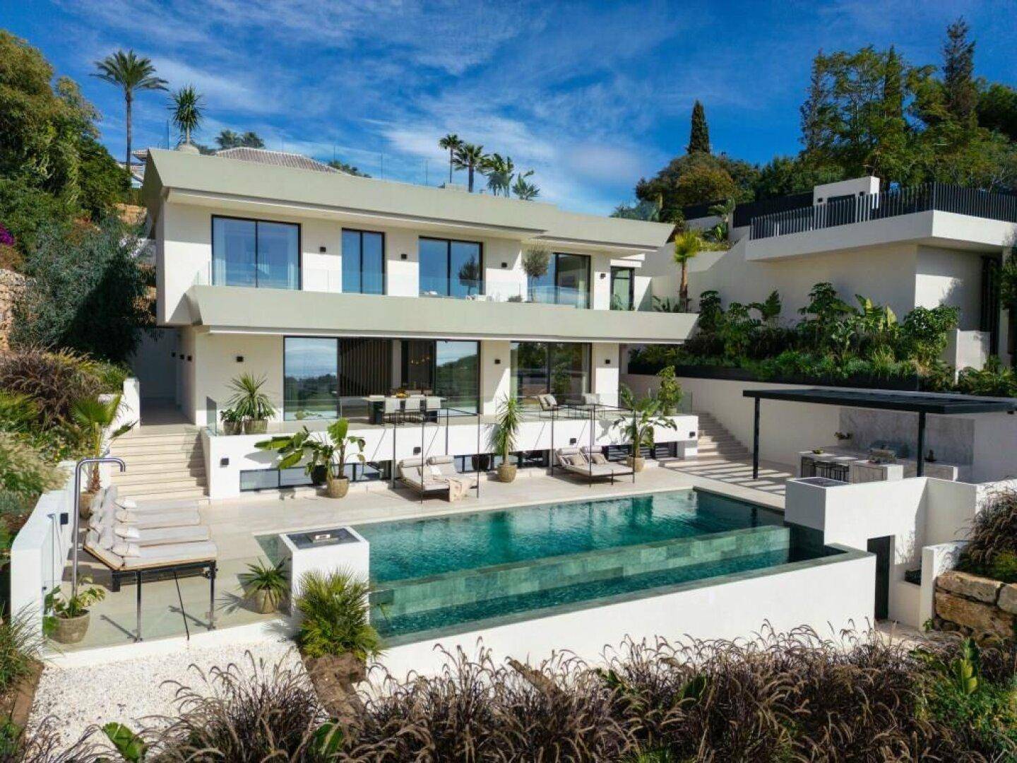 Beeindruckende moderne Villa mit Infinity-Pool, gestufter Architektur und weitläufiger mediterraner Landschaftsgestaltung.
