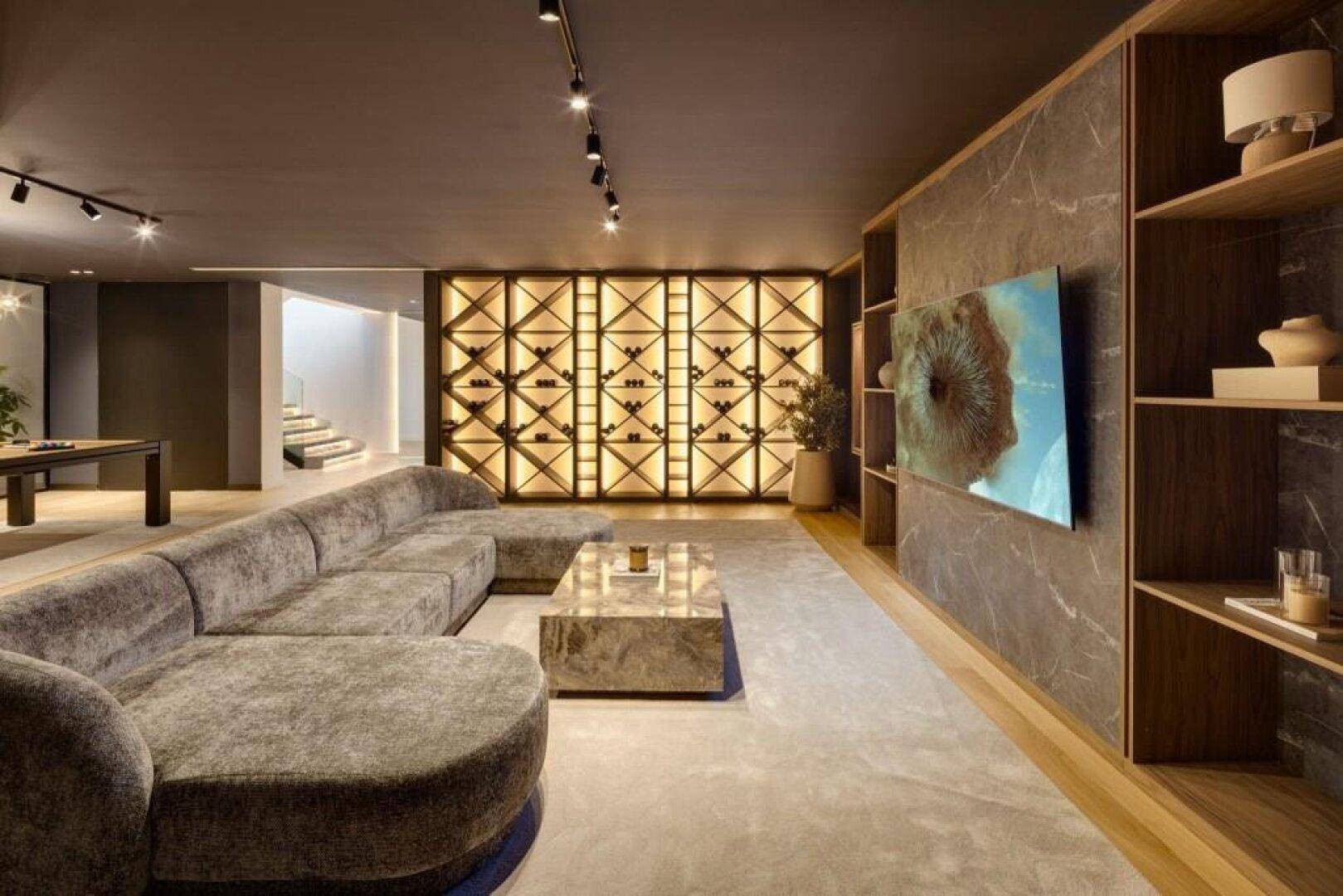 Gemütliches Wohnzimmer mit großem Sofa, modernem Couchtisch und einer beeindruckenden beleuchteten Weinwand.