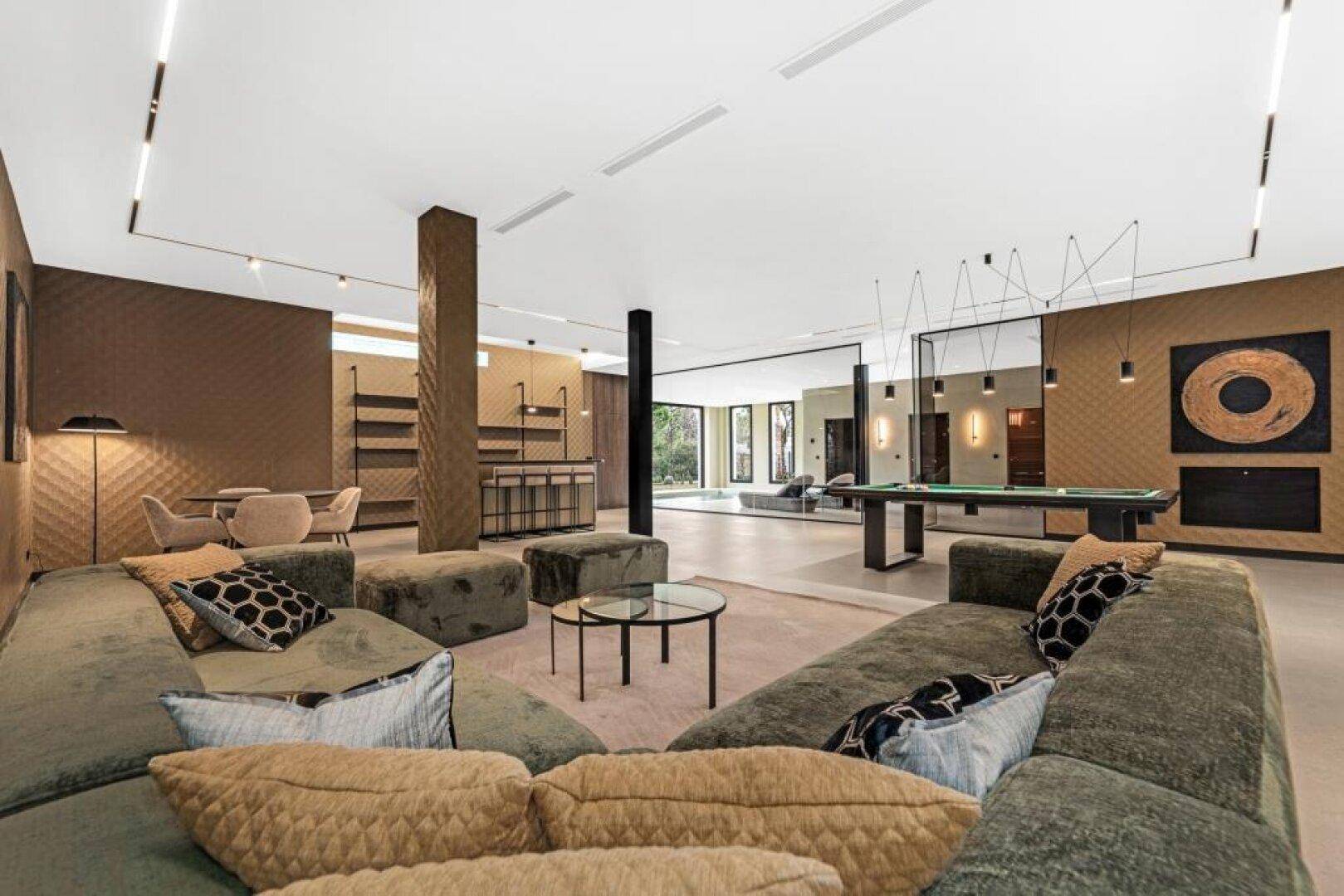 Geräumiger Unterhaltungsbereich mit Billardtisch, bequemen Sofas und moderner Einrichtung.