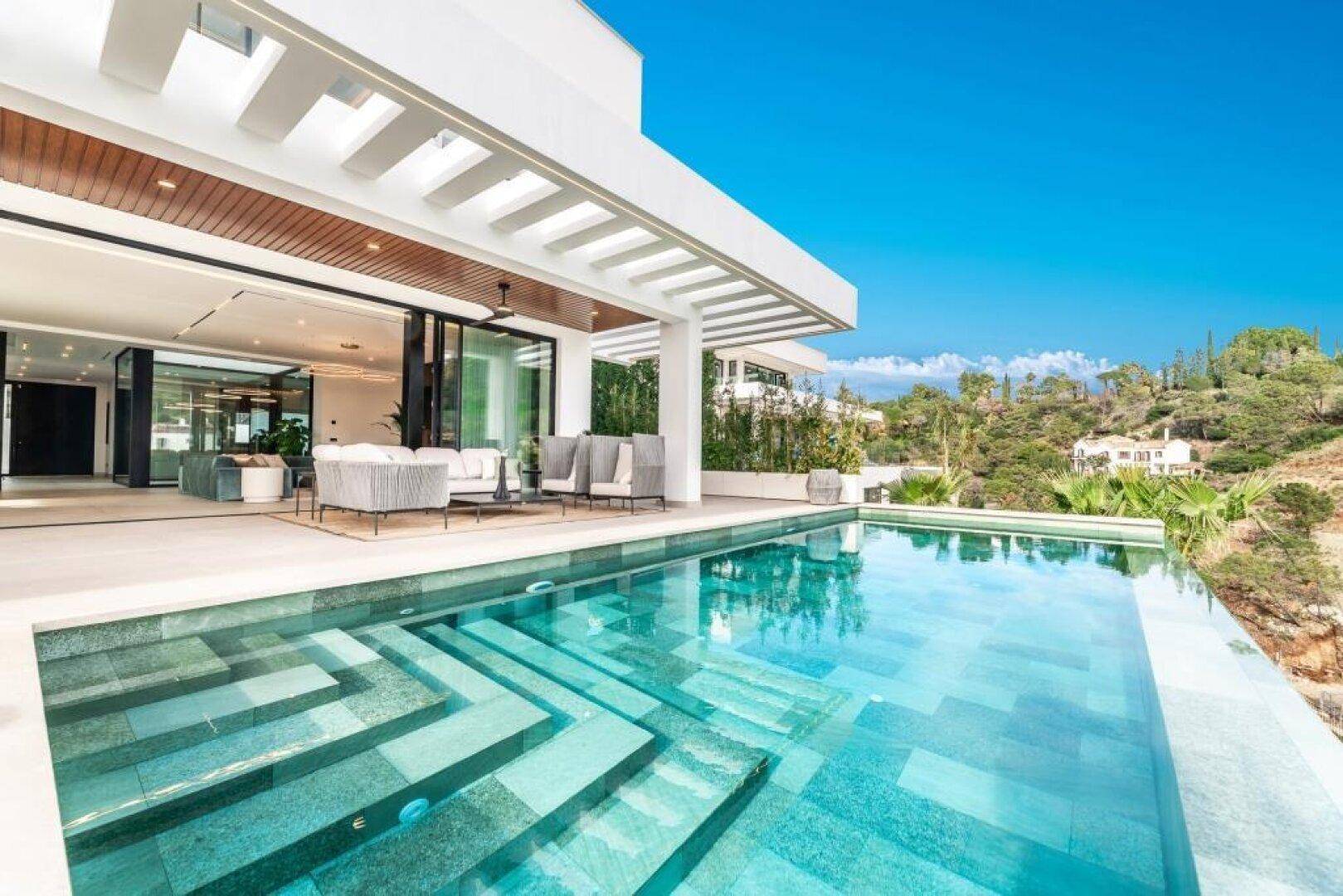 Sonniger Terrassenbereich mit Infinity-Pool und Blick auf die umliegende Landschaft.