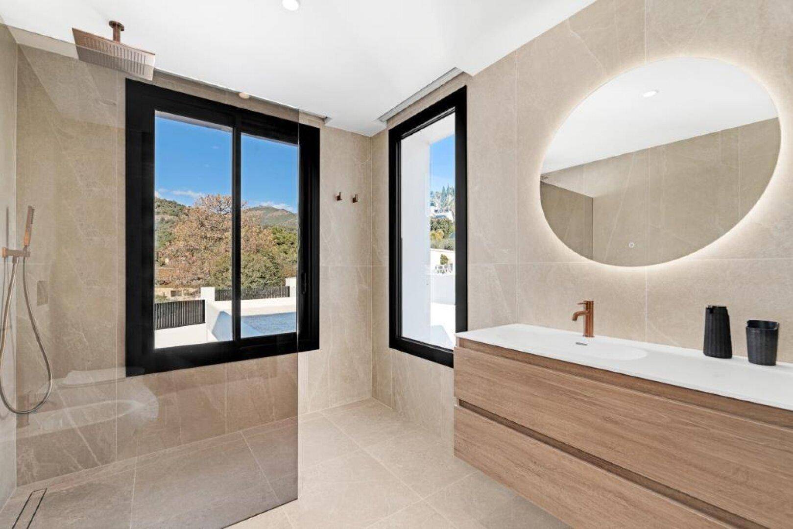 Modernes Badezimmer mit beleuchtetem Spiegel, Einzelwaschbecken und großer Dusche.