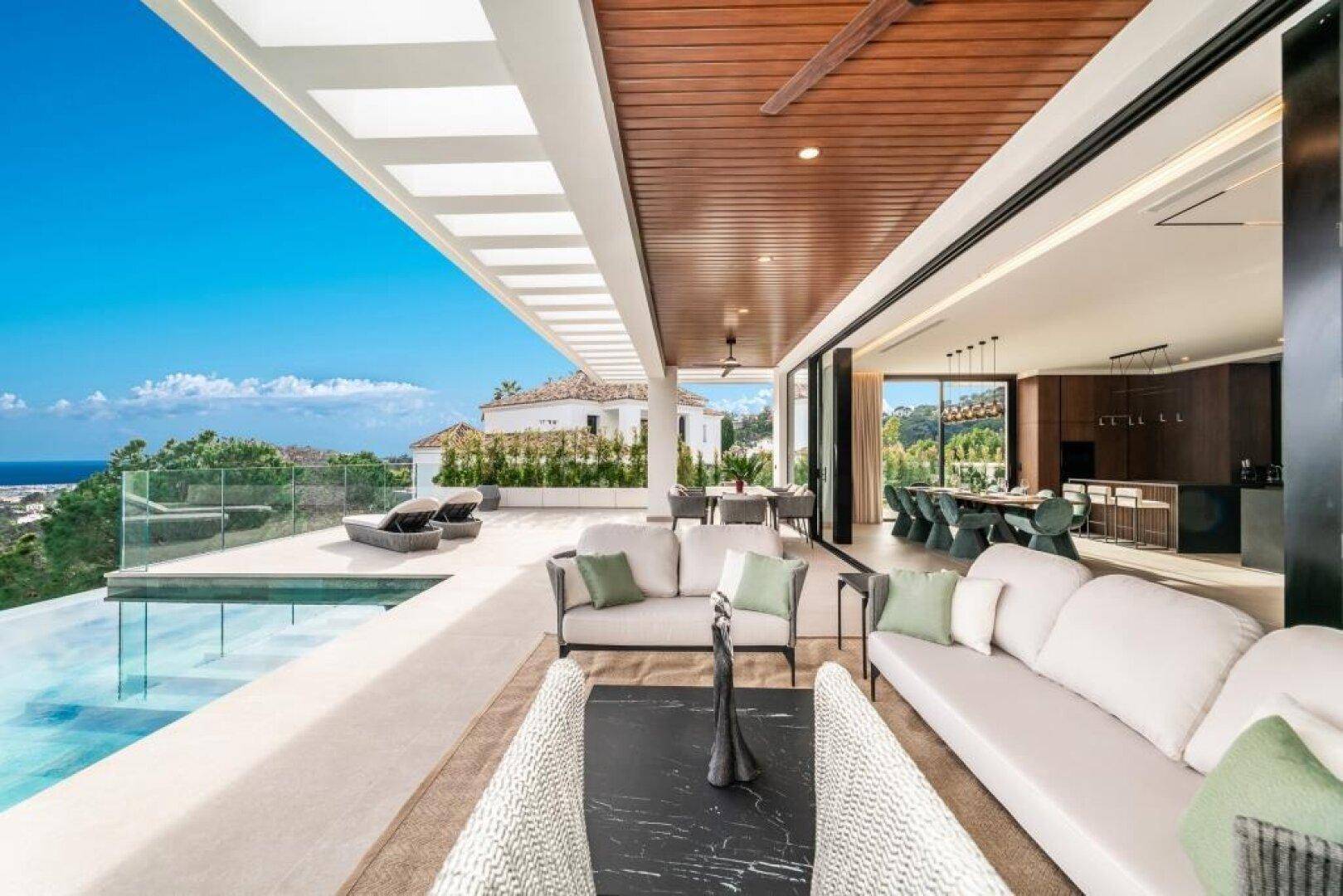 Geräumige Terrasse mit bequemen Sitzgelegenheiten, Infinity-Pool und atemberaubendem Meerblick.