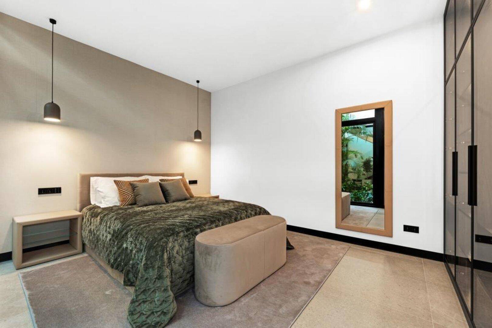 Modernes Schlafzimmer mit großem Bett, minimalistischer Einrichtung und integriertem Kleiderschrank.