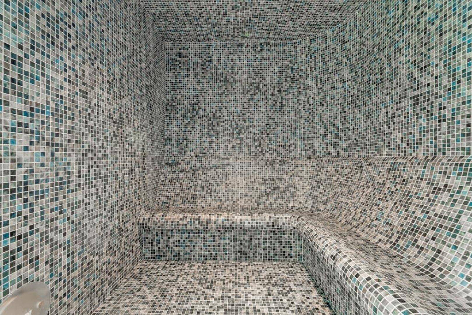 Modernes Dampfbad mit kleinen Mosaikfliesen und integrierter Sitzbank für pure Entspannung.