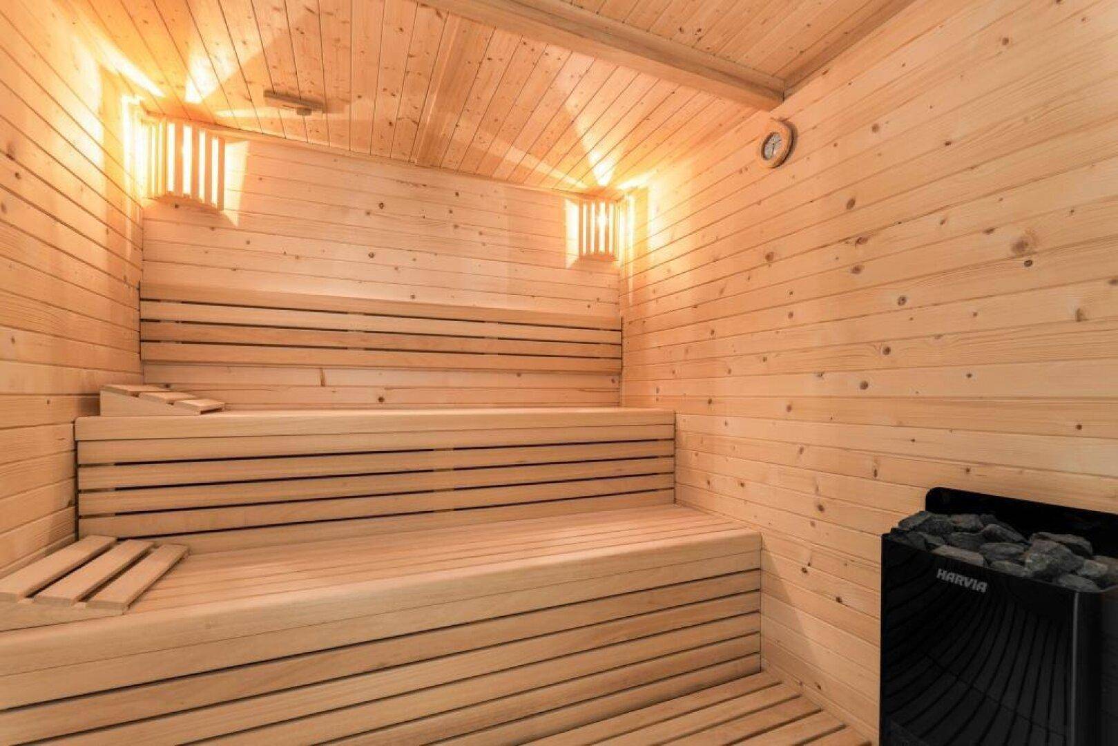 Traditionelle Holzsauna mit mehreren Sitzebenen und Saunaofen, perfekt zum Entspannen.