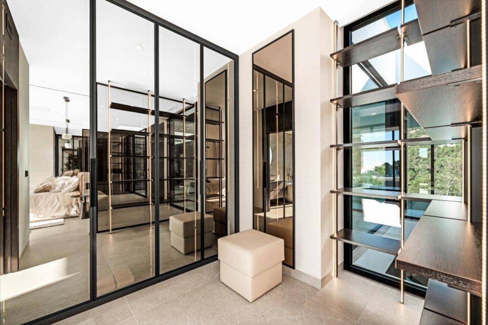Geräumiger begehbarer Kleiderschrank mit Spiegeltüren und offenen Regalen, elegant und funktional.