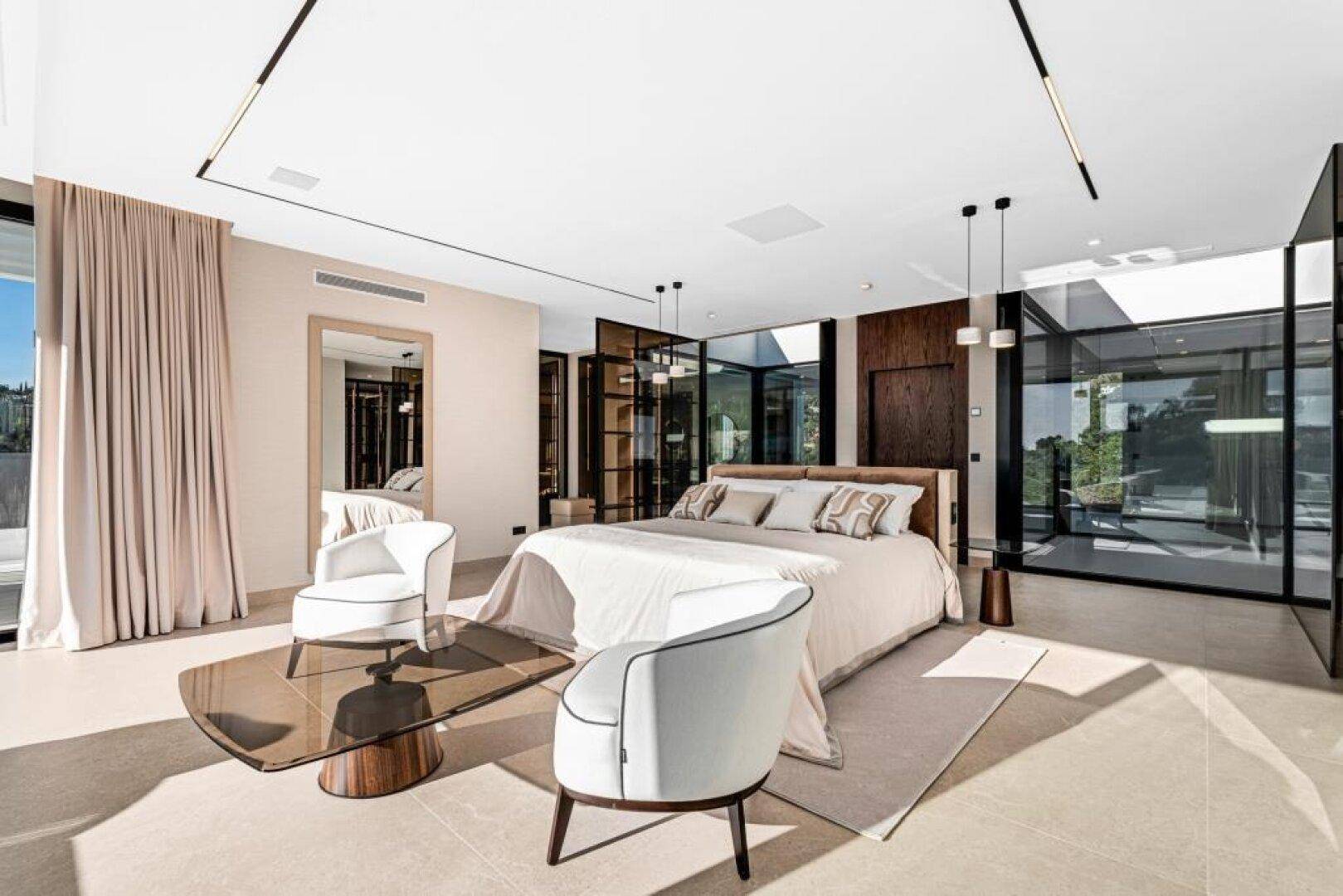 Helles Schlafzimmer mit modernem Design, großen Fenstern und Zugang nach draußen, sehr einladend.