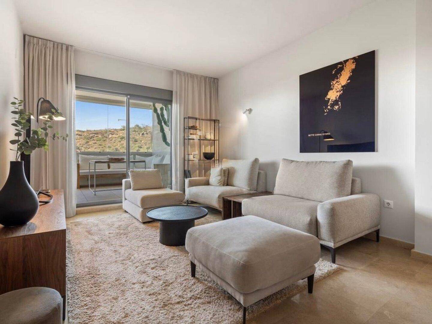 Gemütliches Wohnzimmer mit hellen Sofas, Teppich und Zugang zur Terrasse.