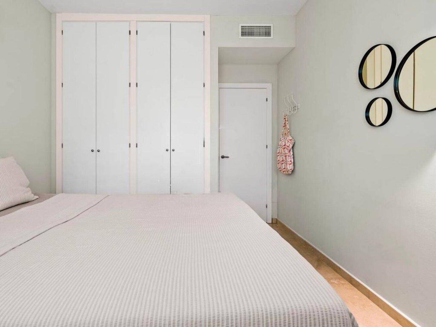 Schlafzimmer mit Einbauschränken und Klimaanlage, in hellen Farbtönen gehalten.