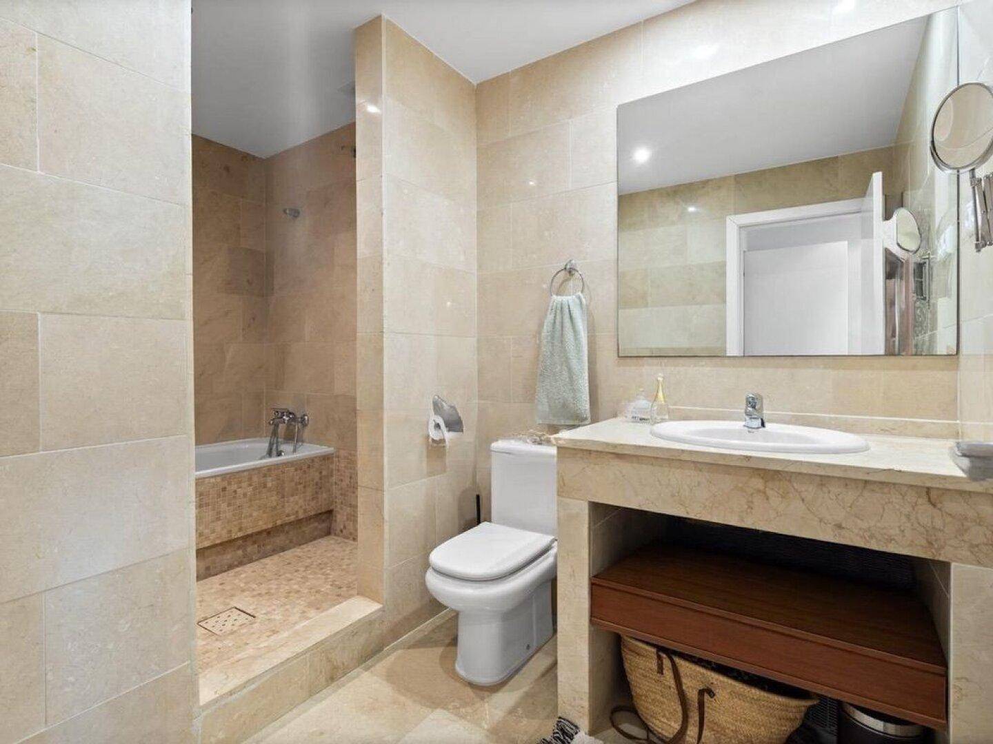 Modernes Badezimmer mit beigefarbenen Fliesen, Badewanne und Waschtisch.