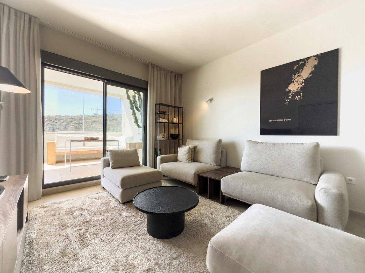 Helles Wohnzimmer mit bequemen Sofas, Teppich und Zugang zur Terrasse.