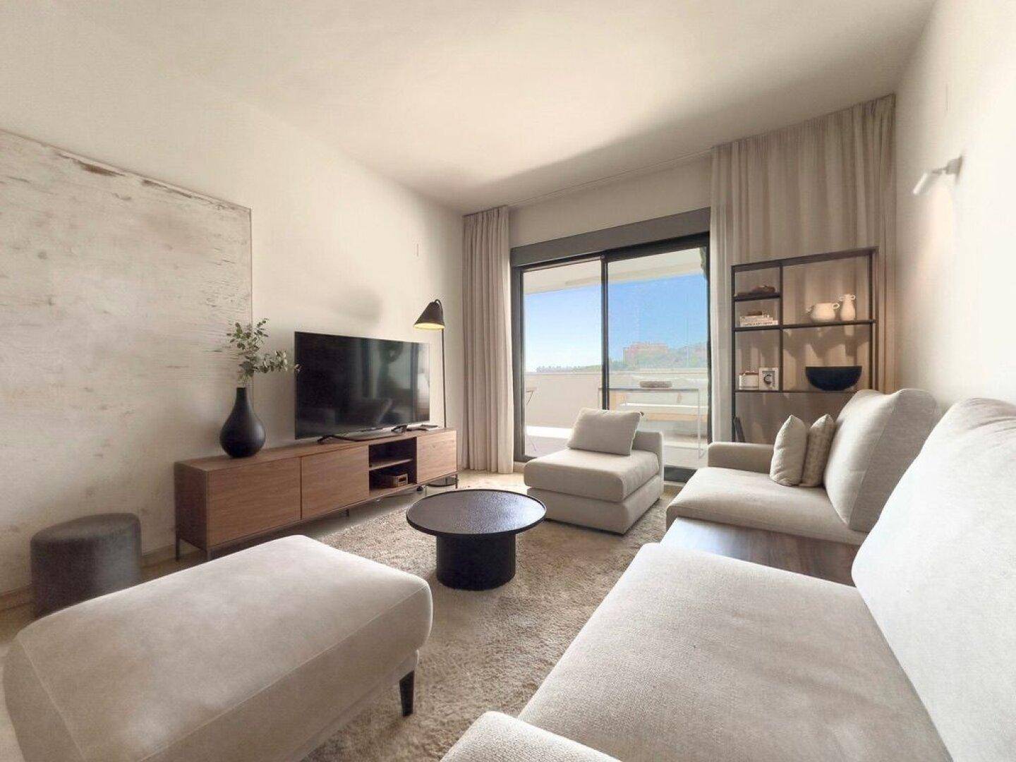 Modern eingerichtetes Wohnzimmer mit großem Fernseher und Zugang zur Terrasse.