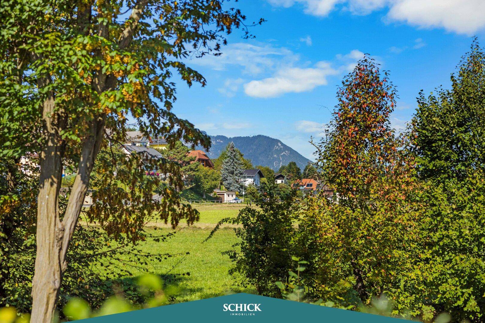 Idyllischer Blick ins Grüne mit Bäumen und Hügeln im Hintergrund, typisch für die ländliche Umgebung.