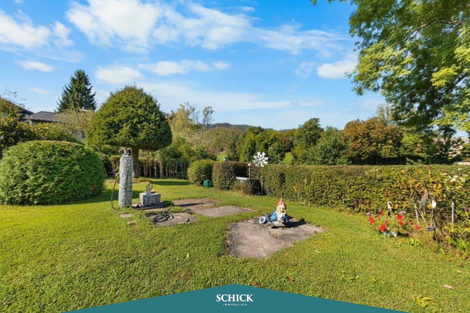 Gepflegter Gartenbereich mit Rasen, Hecken und dekorativen Elementen, darunter Gartenzwerge.