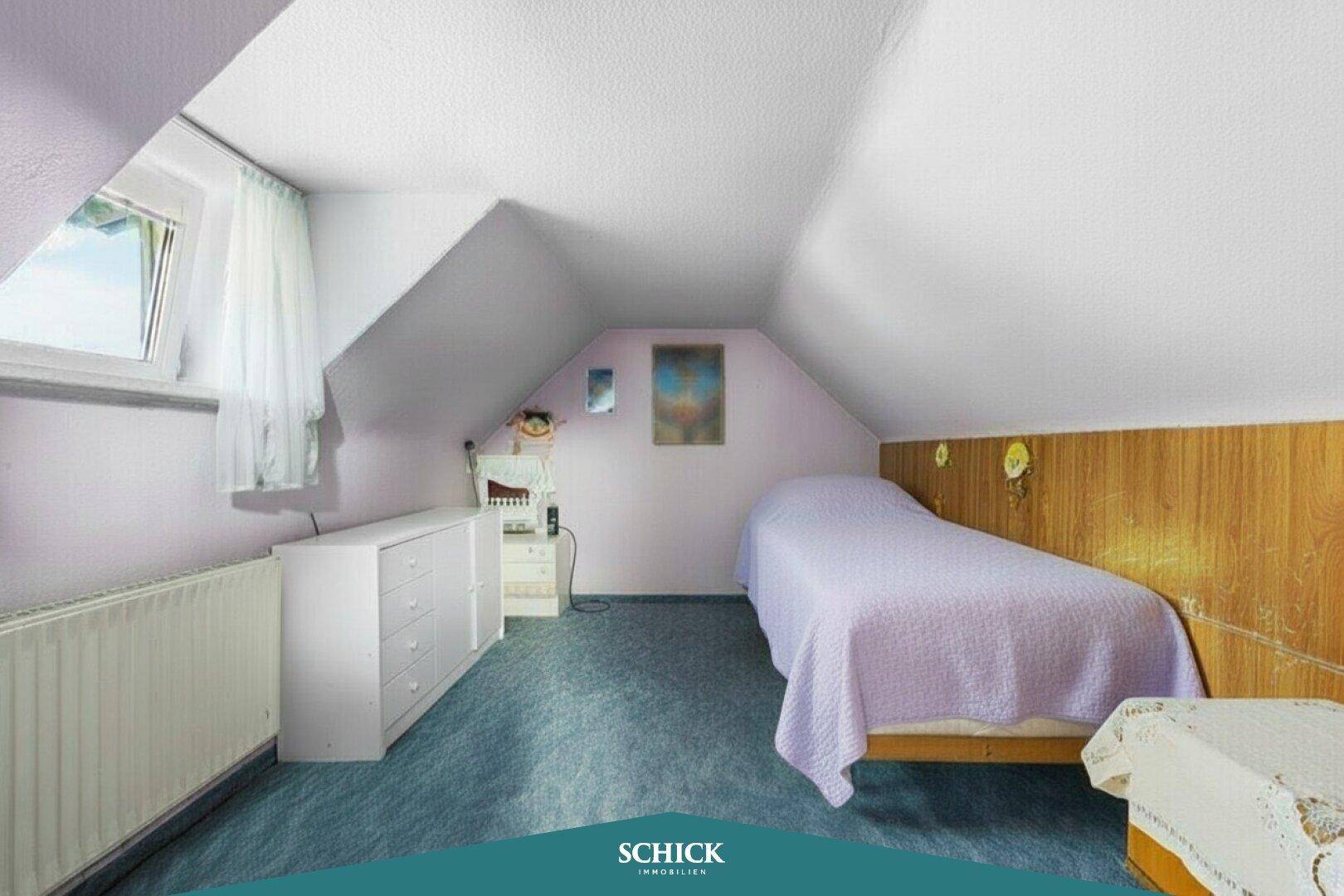 Schlafzimmer im Dachgeschoss mit Dachschrägen, Teppichboden und Fenster.