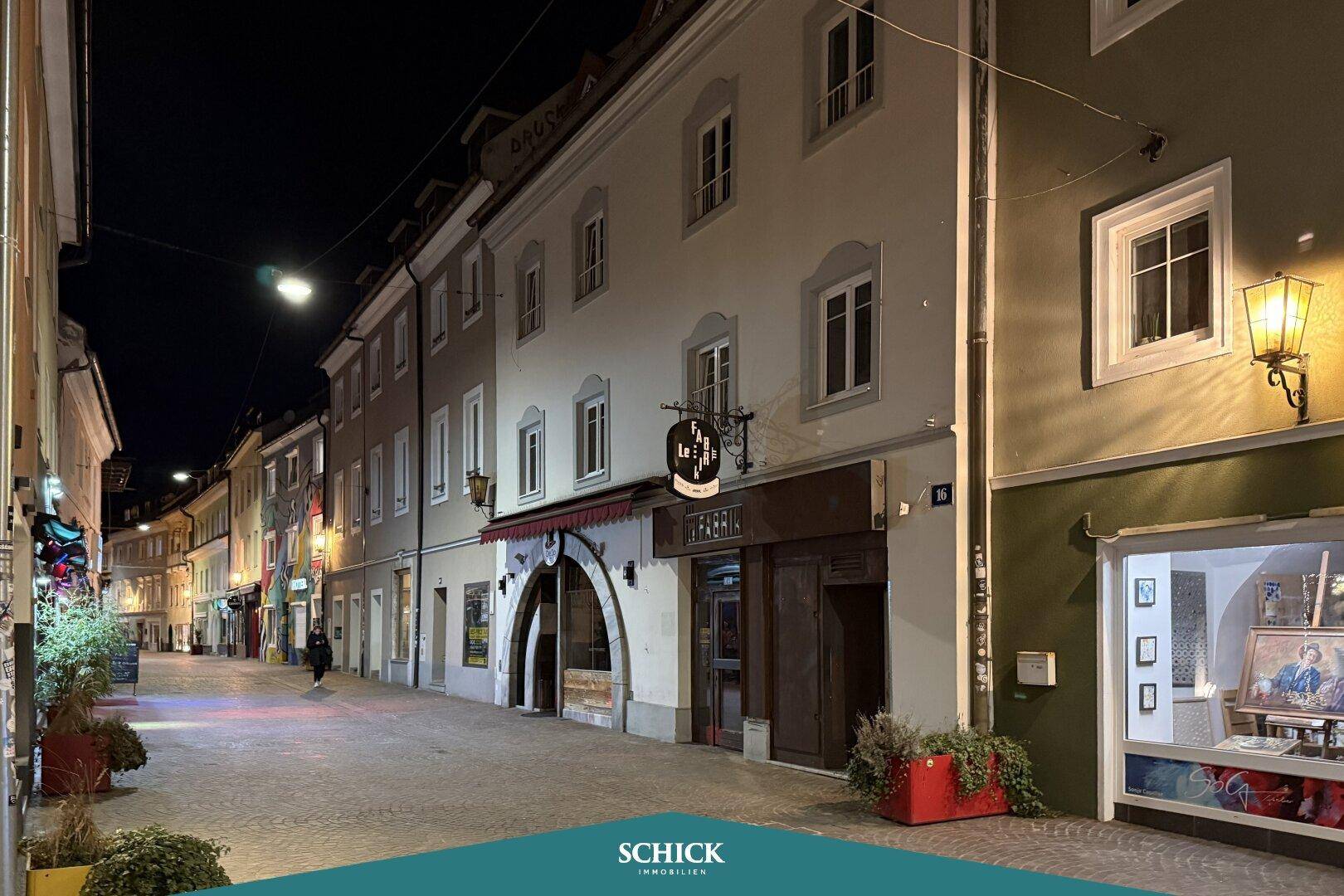 Fassade eines Gebäudes bei Nacht mit dem Schriftzug "FABRIK" und beleuchteten Fenstern.