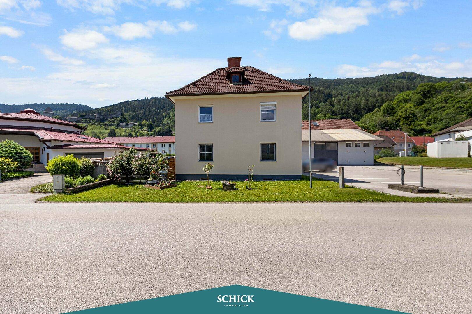 Vorderansicht des Hauses mit gepflegtem Vorgarten und Blick auf die Straße und Umgebung.