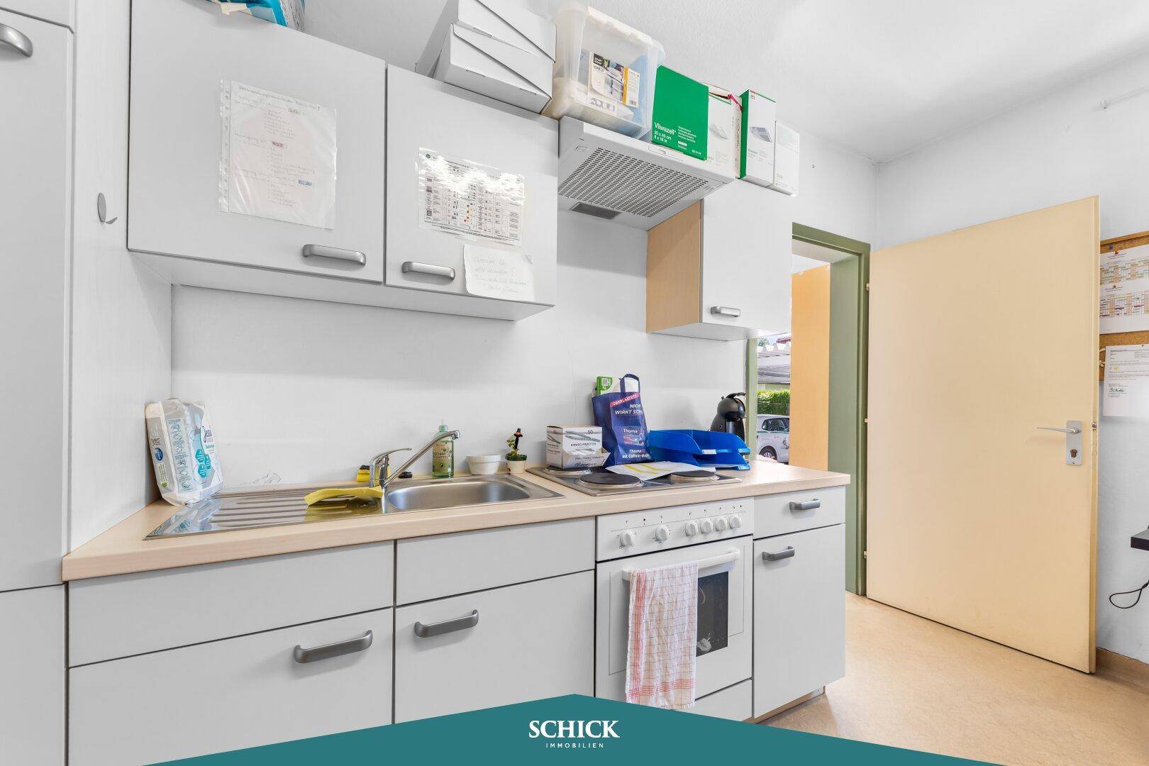 Einfache Küchenzeile mit Spüle, Herd und Oberschränken, ideal für ein kleines Büro.