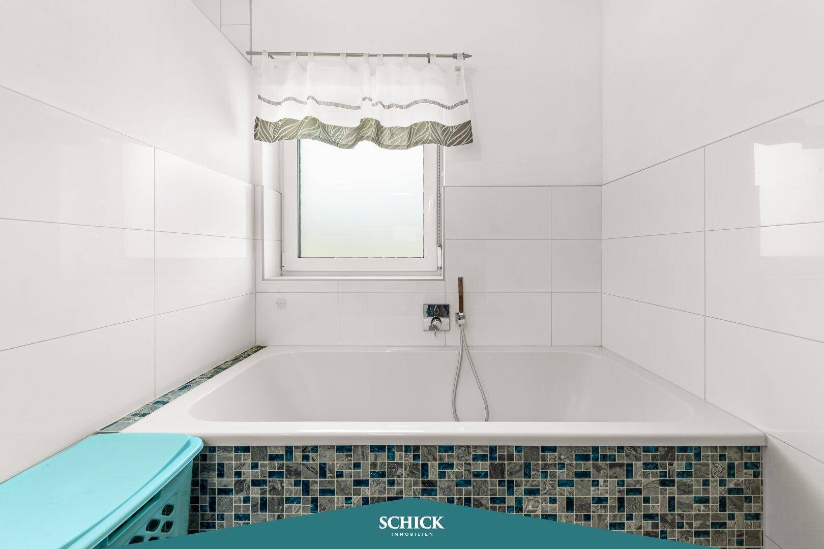 Badewanne mit farbigen Mosaikfliesen und Fenster für natürliches Licht im Badezimmer.