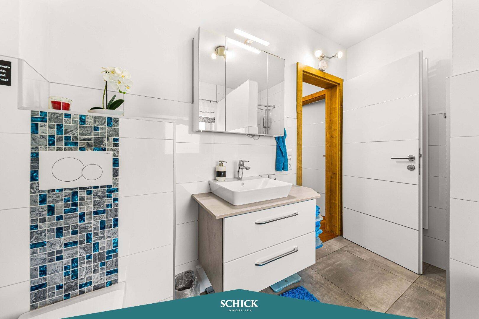Badezimmer mit wandhängendem WC, modernem Waschtisch und Spiegelschrank.