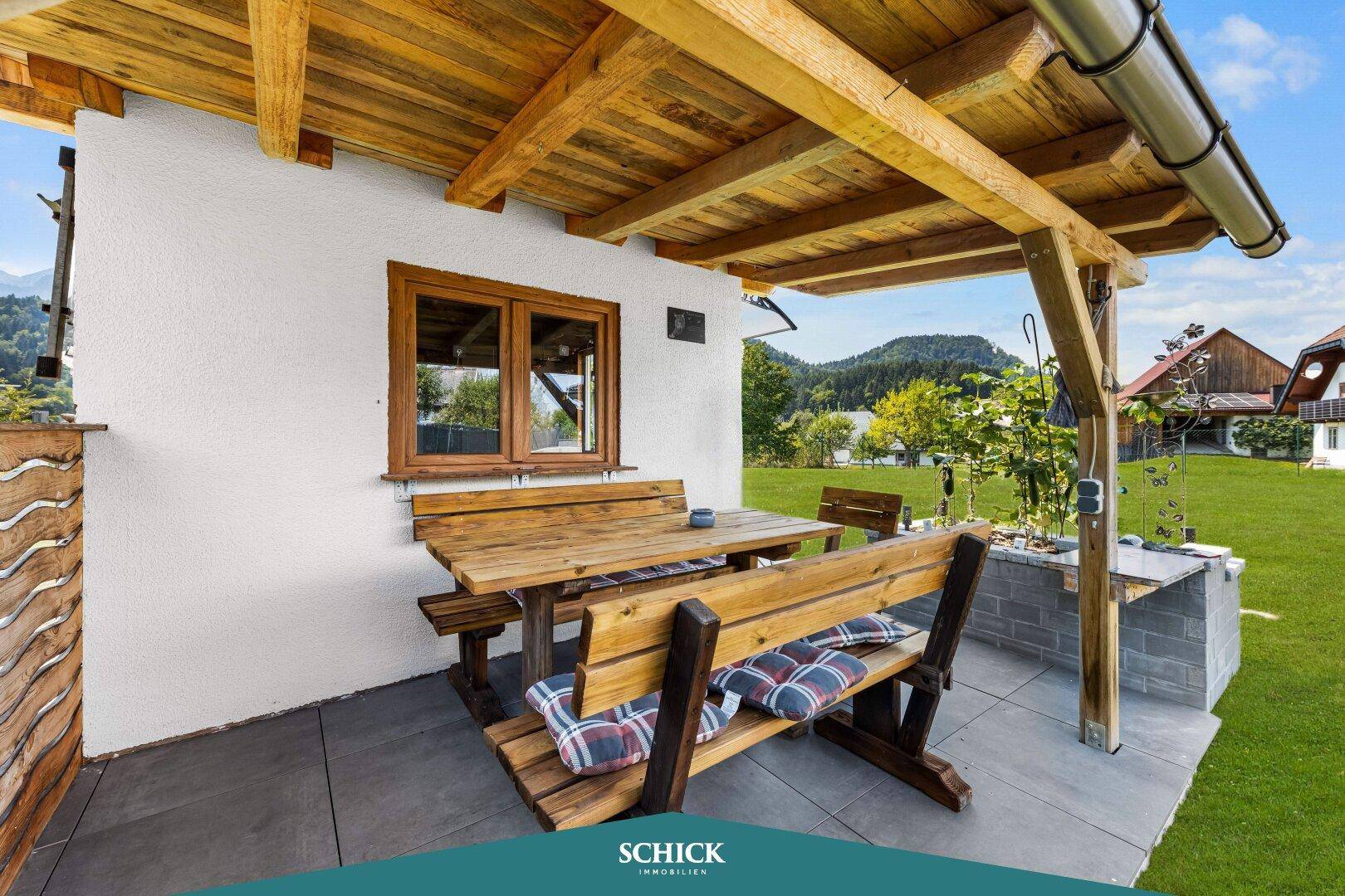 Rustikale überdachte Terrasse mit Holzsitzgruppe und integriertem Grillbereich.