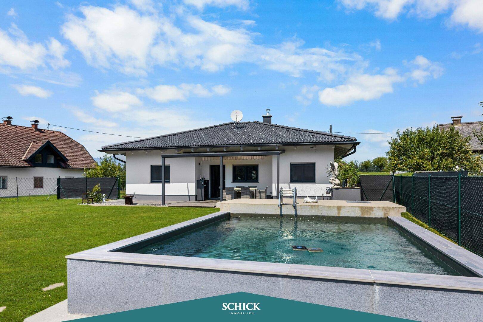 Sonniger Gartenbereich mit Swimmingpool und Blick auf das moderne Einfamilienhaus.