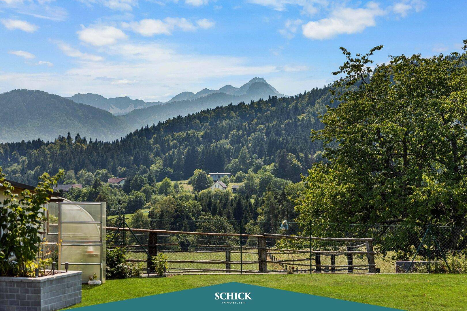 Großer Garten mit weitem Blick auf die Berge und ein kleines Gewächshaus.