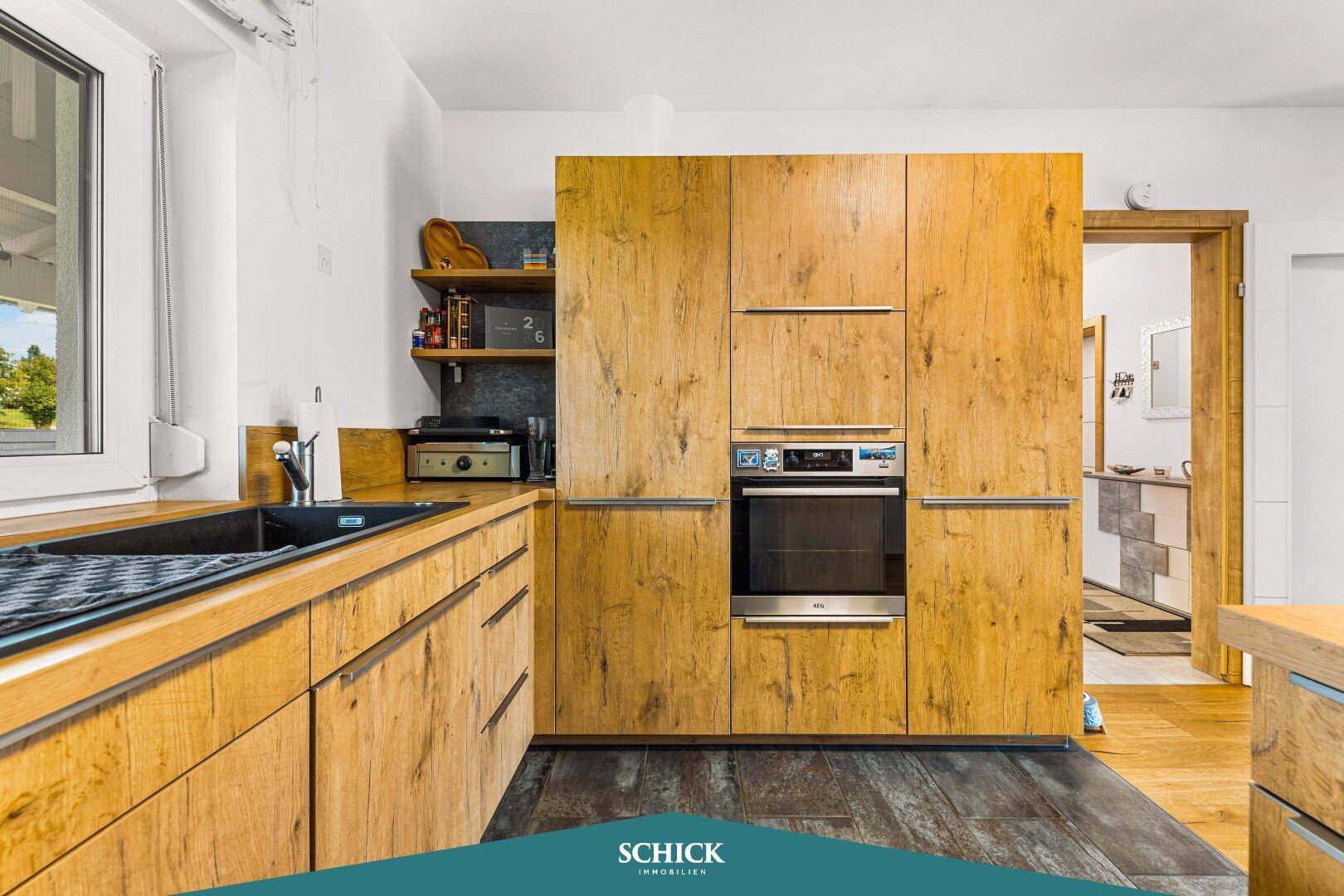 Funktionale Küche mit Holzschränken, modernen Geräten und Zugang zu weiteren Räumen.