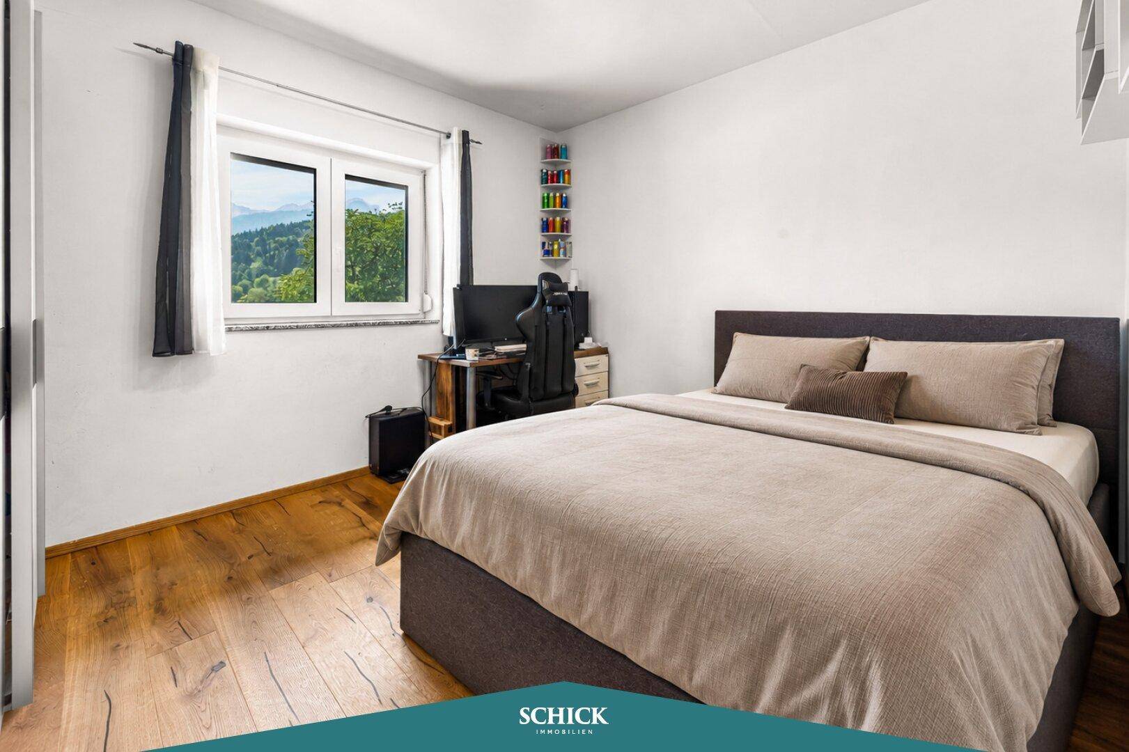 Komfortables Schlafzimmer mit Holzboden, Schreibtisch und Fenster mit Bergblick.